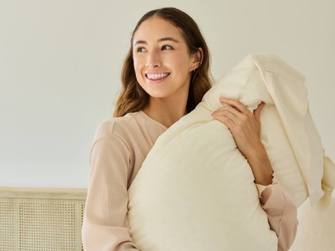 A young woman clutching her Avec Hybrid Pillow and smiling