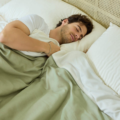 A young man sleeping in his bed made with Avec linen-blend bedding