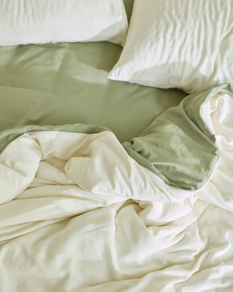 A close up view of Avec linen-blend sheets and duvet on a bed